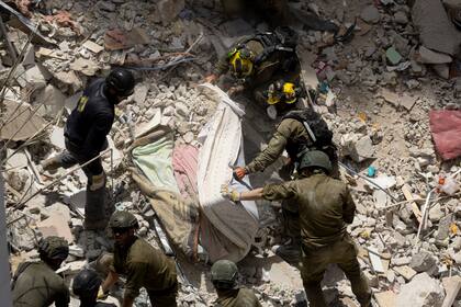 Soldados de emergencia y rescate buscan a personas atrapadas en edificios gravemente dañados tras un ataque con misiles iraníes el 15 de junio de 2025 en Bat Yam, Israel.